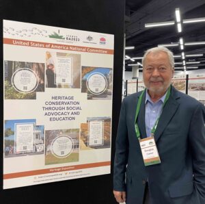 ICOMOS-USA President Douglas Comer stands next to our national committee poster in the General Assembly Hall.