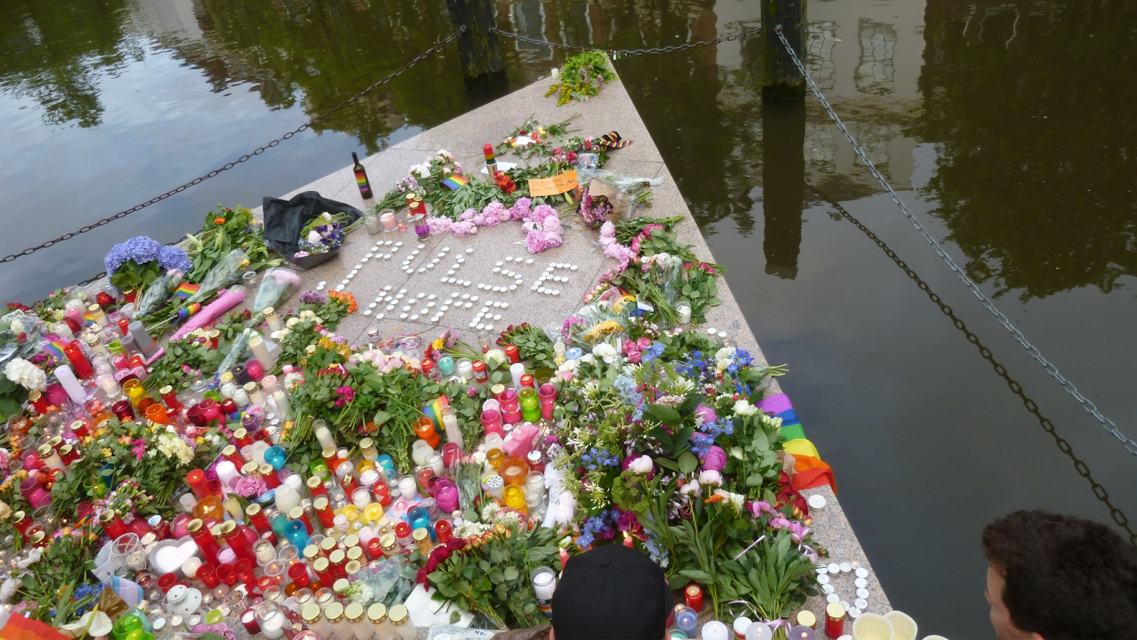 Flowers and candles surround the message “Pulse hope” on the canal triangle of the Homomonument to honor those killed at the Pulse nightclub shooting that occurred in Orlando, Florida, in 2016. Image Credit: Wikimedia Commons